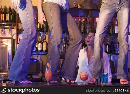 Young people dancing on a bar counter with bartender looking on