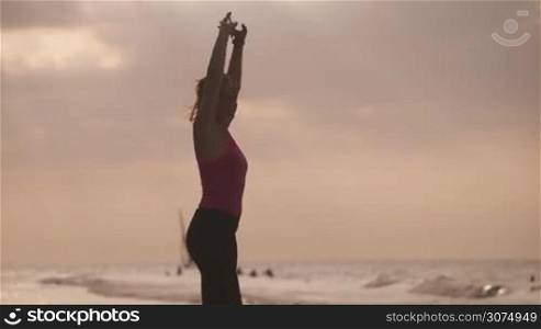 Young people doing sport activity, girl running on the beach, woman jogging near the sea. Leisure, healthy recreation, sports exercising, training, working out. Female athlete stretching, slow motion
