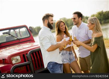 Young people drinking and having fun by car outdoor at hot summer day