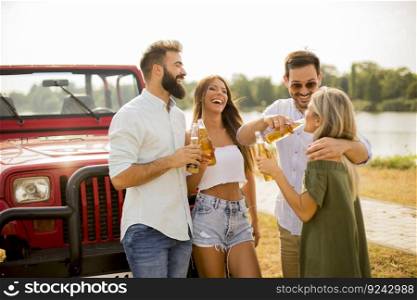 Young people drinking and having fun by car outdoor at hot summer day