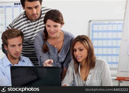 Young people gathered round a laptop