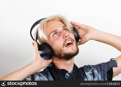 Young people, happiness and leisure concept. Passionate music lover joyful stylish guy with headphones listening music, relaxing enjyoing. cool guy having fun listens to music in headphones