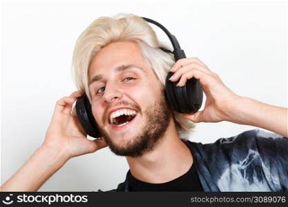 Young people, happiness and leisure concept. Passionate music lover joyful stylish guy with headphones listening music, relaxing enjyoing. cool guy having fun listens to music in headphones