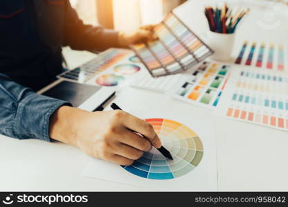 Young people holding pen pointing at color sheet in business office.