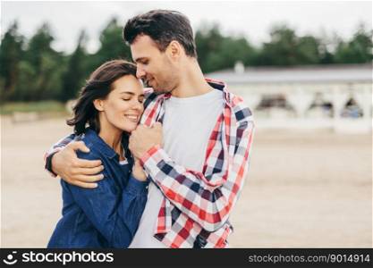 Young people in love sped time outdoor, embrace each other, feel support and have leisure, glad to spend time together. Young handsome brunet man hugs his girlfriend passionately. Young people in love outdoor