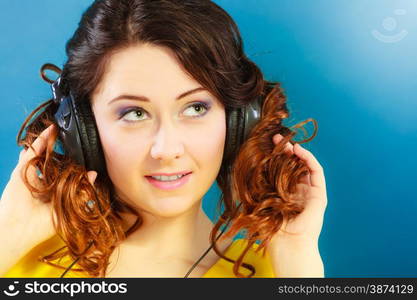 Young people leisure relax concept. Closeup teen cute girl in big headphones listening music mp3 relaxing on blue background