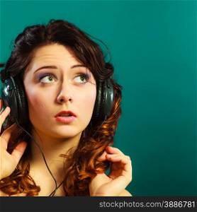 Young people leisure relax concept. Closeup teen cute girl in big headphones listening music mp3 relaxing on green blue background