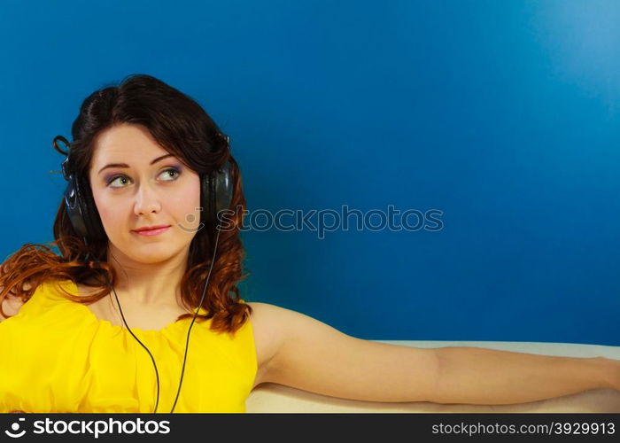 Young people leisure relax concept. Closeup teen cute girl in big headphones listening music mp3 relaxing on blue background