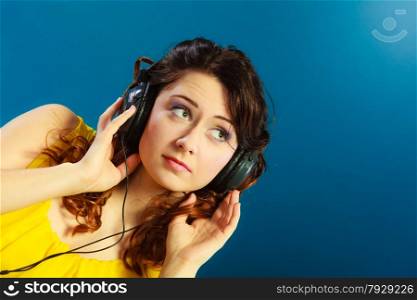 Young people leisure relax concept. Closeup teen cute girl in big headphones listening music mp3 relaxing on blue background