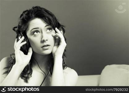 Young people leisure relax concept. Closeup teen cute girl in big headphones listening music mp3 relaxing black and white photo