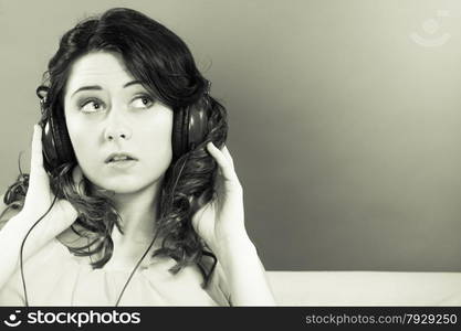 Young people leisure relax concept. Closeup teen cute girl in big headphones listening music mp3 relaxing black and white photo