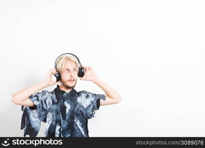 Young people, relax and passion concept. Passionate music lover stylish guy with headphones listening music, relaxing enjyoing, studio shot on white copy space. cool guy having fun listens to music in headphones