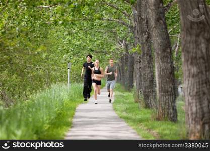 Young people running on walkway by trees
