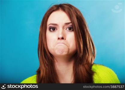 Young people teenage concept - teen funny girl making silly face, unhappy face expression on blue