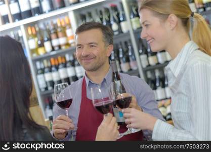 young people toasting red wine with merchant in cellar