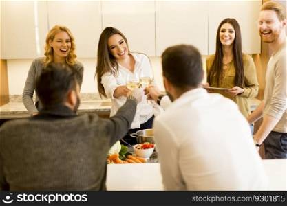 Young people toasting white wine in modern kitchen