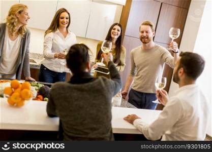 Young people toasting with white wine in the kitchen