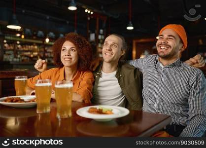 Young people watching football game at sports bar. Diverse interracial soccer fans smiling feeling happy drinking beer and cheering for favorite team, celebrating victory. Young people watching football game at sports bar