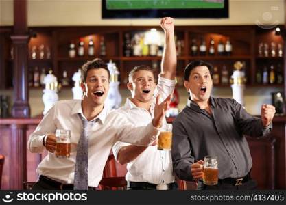 Young people with beer watching football in a bar