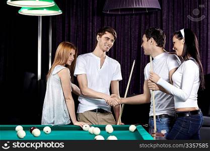 Young people with cue at a billiard table