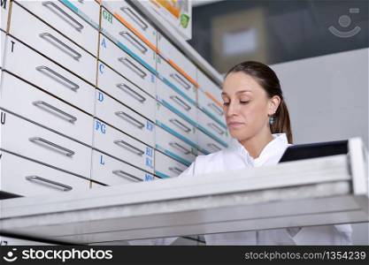 Young pharmacist woman looking for medicine in the store desk
