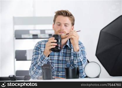 young photographer cleaning lenses in his studio