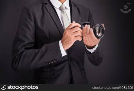 Young photographer man holding camera isolated on black background