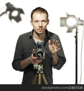 Young photographer taking pictures with medium-format camera in studio, behind him there is lightning equipment out of focus, white background