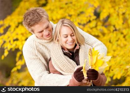 Young playful couple happy picking leaves in autumn park outfit