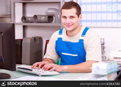 Young plumber in an office working on a computer