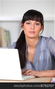 Young poised woman sitting at a laptop computer