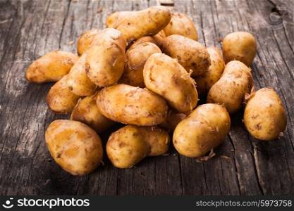 Young potato heap on a wooden background. Potato isolated