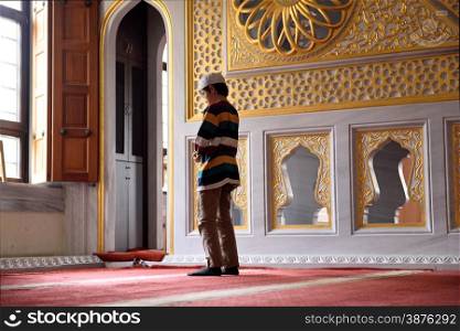 Young praying alone in front of window