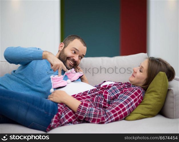 young pregnant couple relaxing on sofa. happy pregnant couple relaxing on sofa couch at home