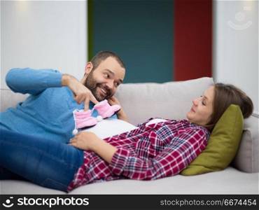 young pregnant couple relaxing on sofa. happy pregnant couple relaxing on sofa couch at home