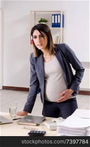 Young pregnant employee working in the office 