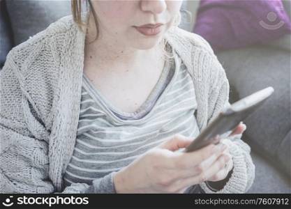 Young pregnant woman at home using her mobile phone