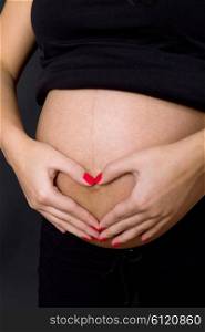 young pregnant woman belly, on a black background
