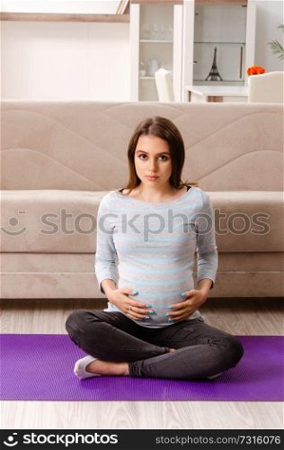 Young pregnant woman doing sport exercises at home 