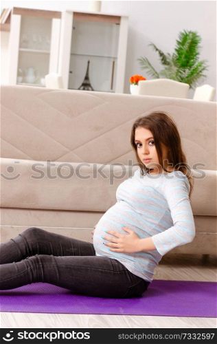 Young pregnant woman doing sport exercises at home 
