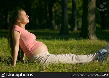 young pregnant woman enjoying the sun in the park