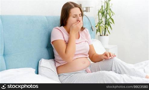 Young pregnant woman feeling sick resting in bed and coughing in hand. Concept of pregnancy healthcare and medical examination. Young pregnant woman feeling sick resting in bed and coughing in hand. Concept of pregnancy healthcare and medical examination.