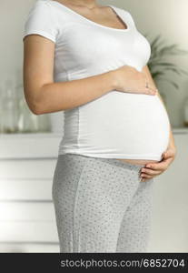 Young pregnant woman in pajamas holding hands on belly