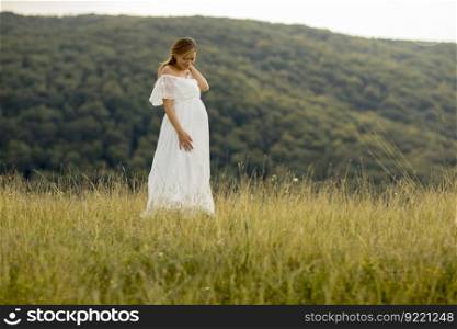 Young pregnant woman relaxing outside in nature at summer day