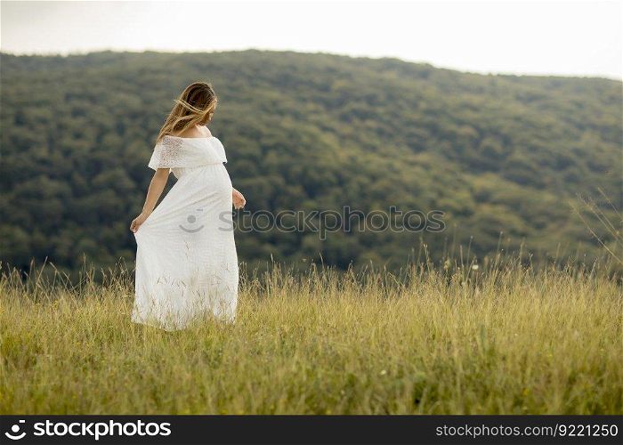 Young pregnant woman relaxing outside in nature at summer day