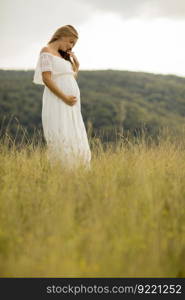 Young pregnant woman relaxing outside in nature at summer day