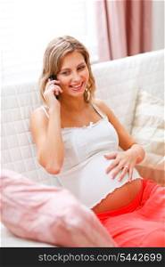 Young pregnant woman sitting on couch and speaking mobile phone&#xA;
