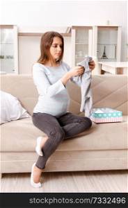Young pregnant woman sitting on the sofa at home 