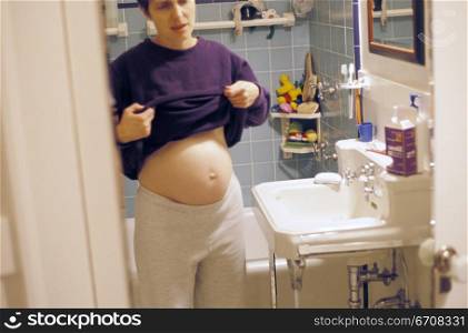 Young pregnant woman standing in the bathroom