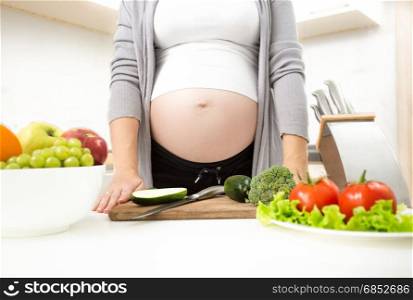 Young pregnant woman standing on kitchen